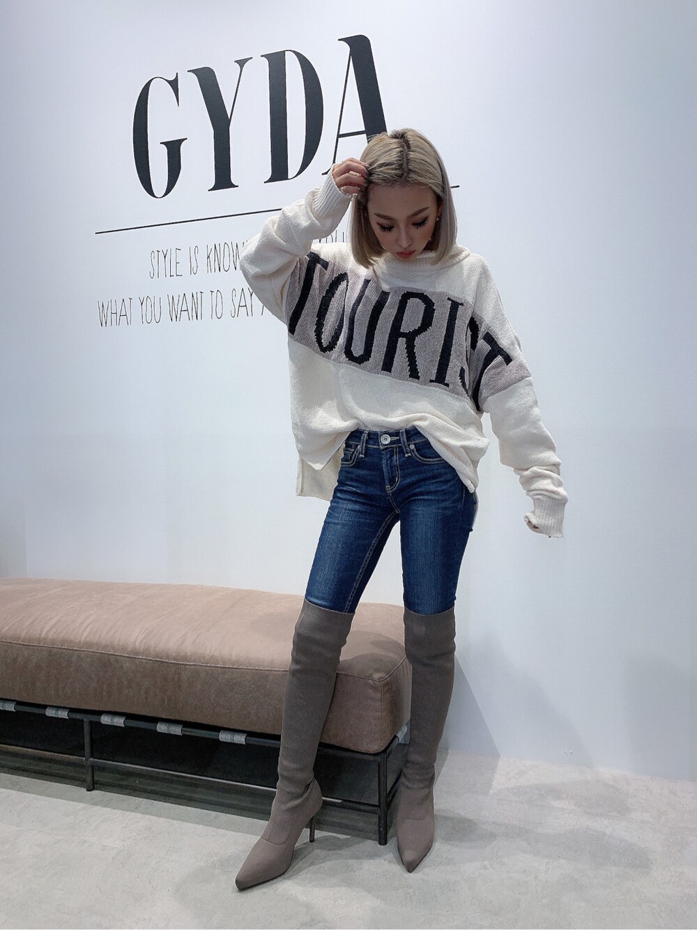 ブルー系のデニムパンツ、ベージュ系のブーツ、ホワイト系のニット/セーターを着用したレディースの秋コーディネートの2枚目の写真