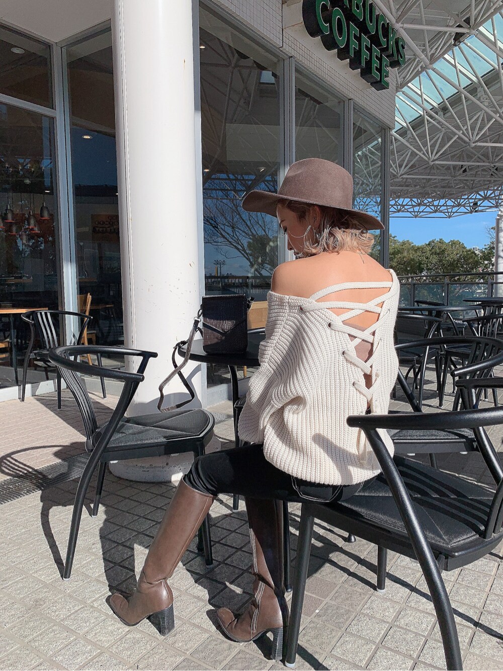 ブラック系のデニムパンツ、ブラウン系のショルダーバッグ、ベージュ系のキャミソールを着用したレディースの冬コーディネートの3枚目の写真