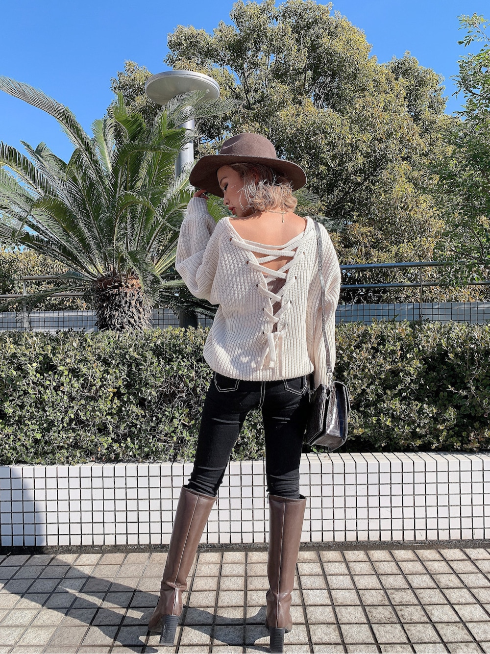 ブラウン系のショルダーバッグ、ベージュ系のキャミソール、ブラック系のデニムパンツを着用したレディースの冬コーディネートの2枚目の写真