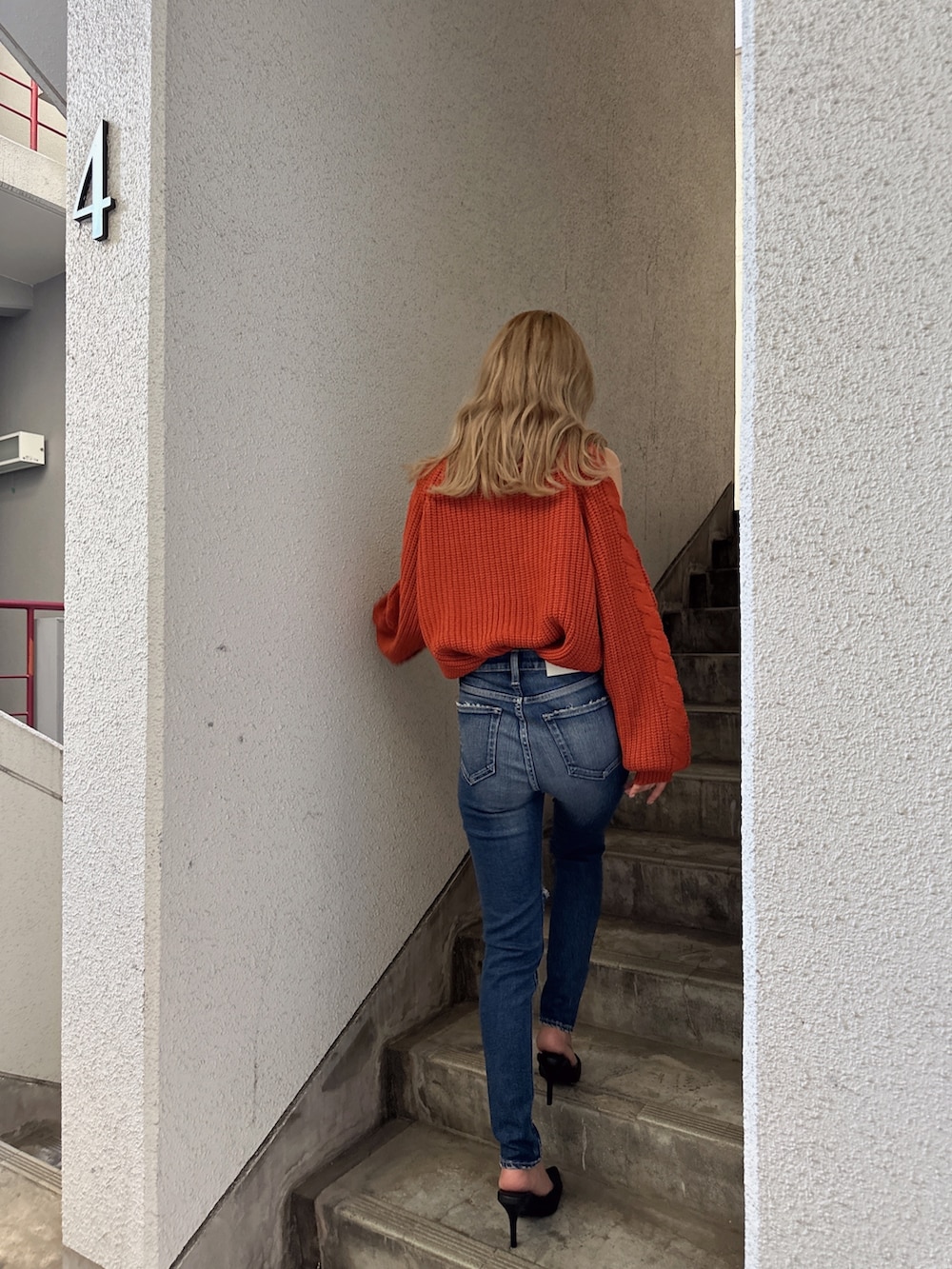 オレンジ系のニット/セーター、ブルー系のデニムパンツ、ブラック系のパンプスを着用したレディースの秋コーディネートの4枚目の写真