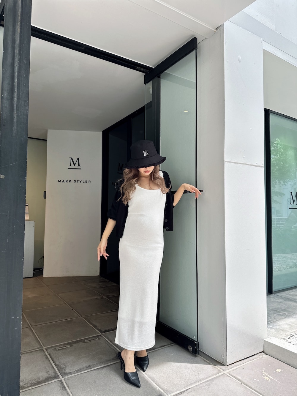 ブラック系のカーディガン/ボレロ、ホワイト系のワンピース、ブラック系のハットを着用したレディースの春コーディネートの3枚目の写真