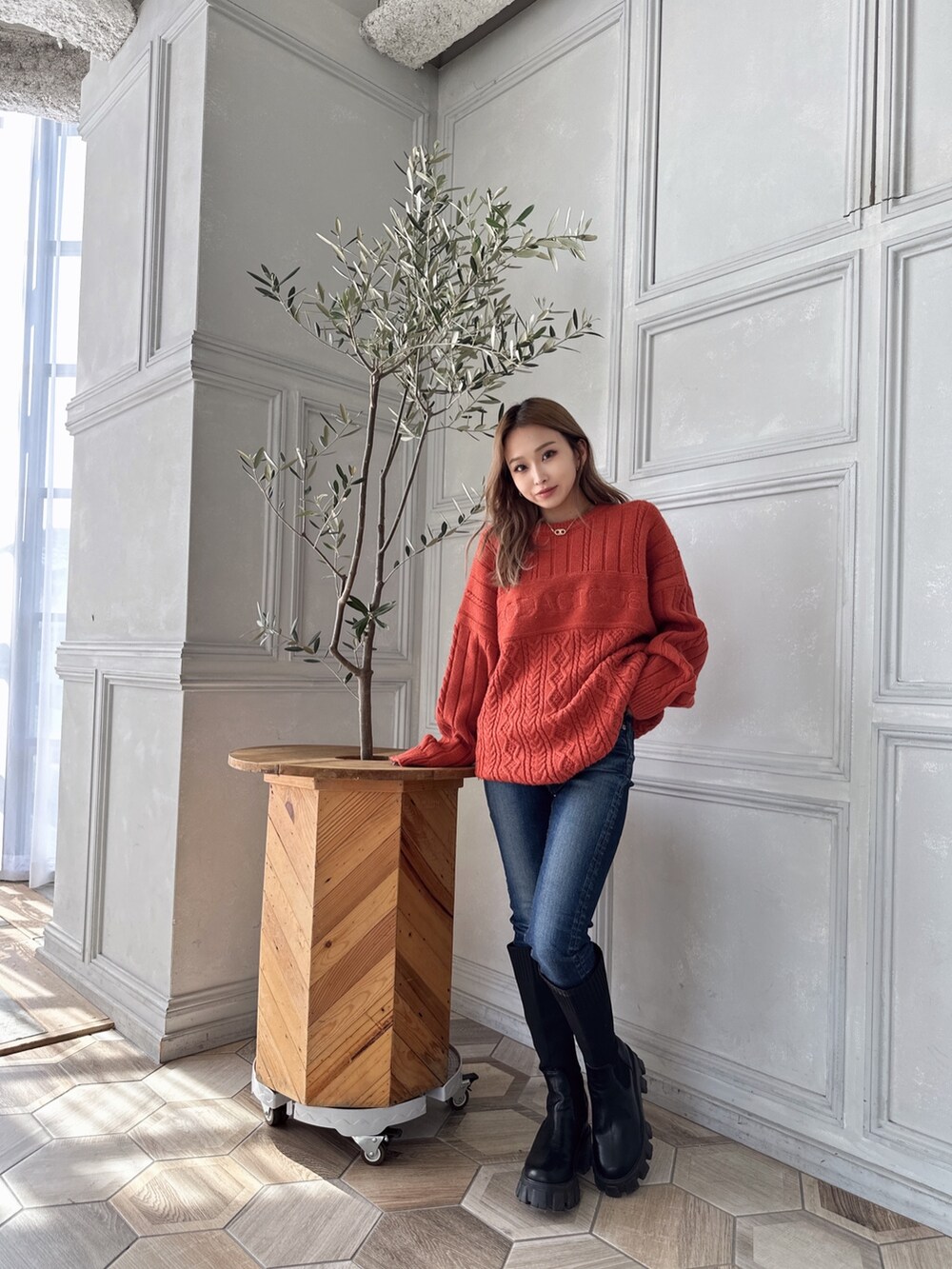 オレンジ系のニット/セーター、ブルー系のデニムパンツ、ブラック系のブーツを着用したレディースの秋コーディネートの4枚目の写真