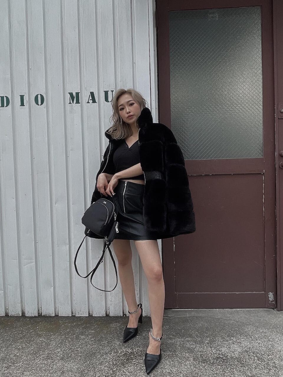 ブラック系のその他アウター、ブラック系のスカート、ブラック系のバックパック/リュックを着用したレディースの冬コーディネートの2枚目の写真