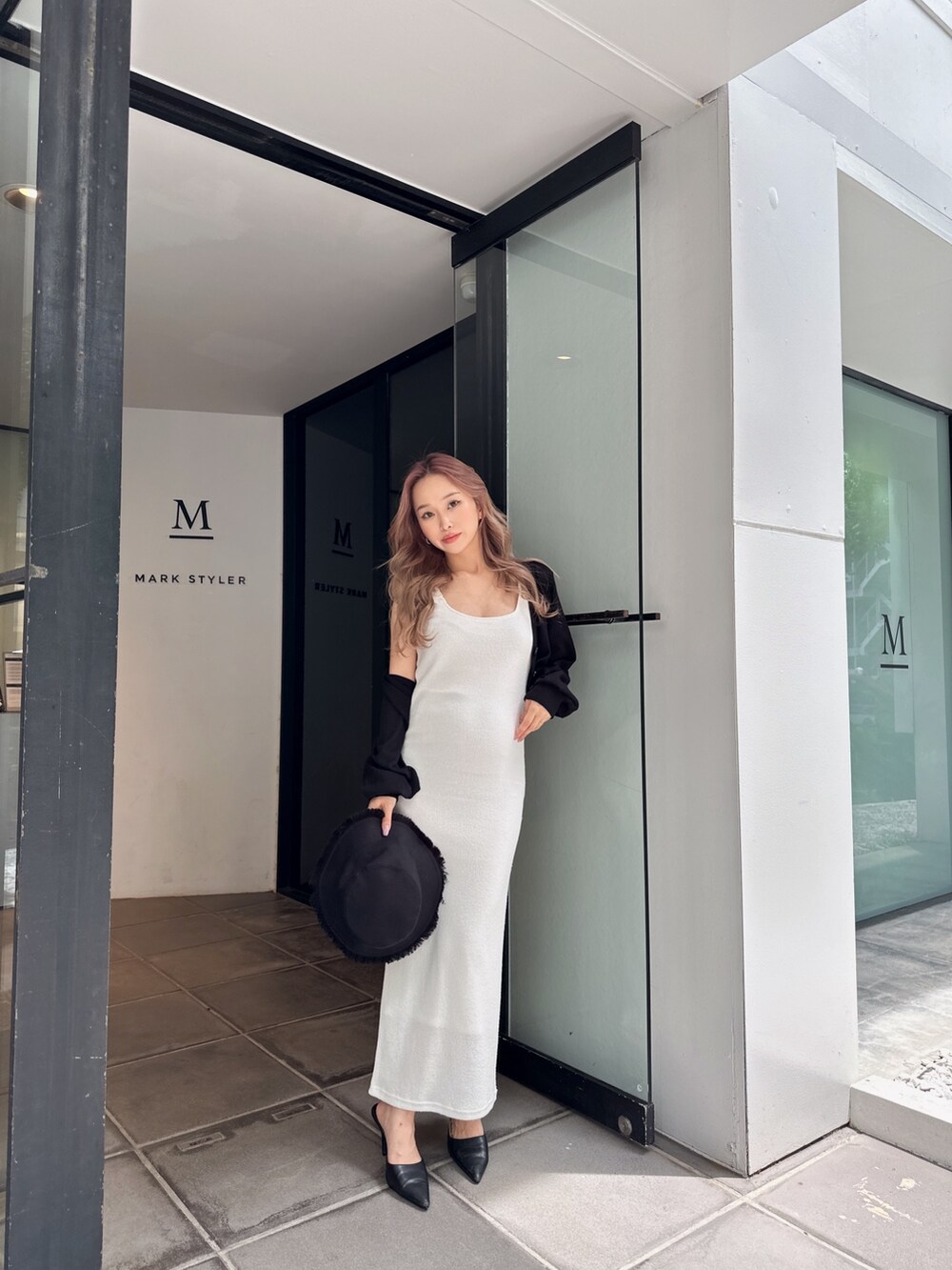 ブラック系のカーディガン/ボレロ、ホワイト系のワンピース、ブラック系のハットを着用したレディースの春コーディネートの2枚目の写真