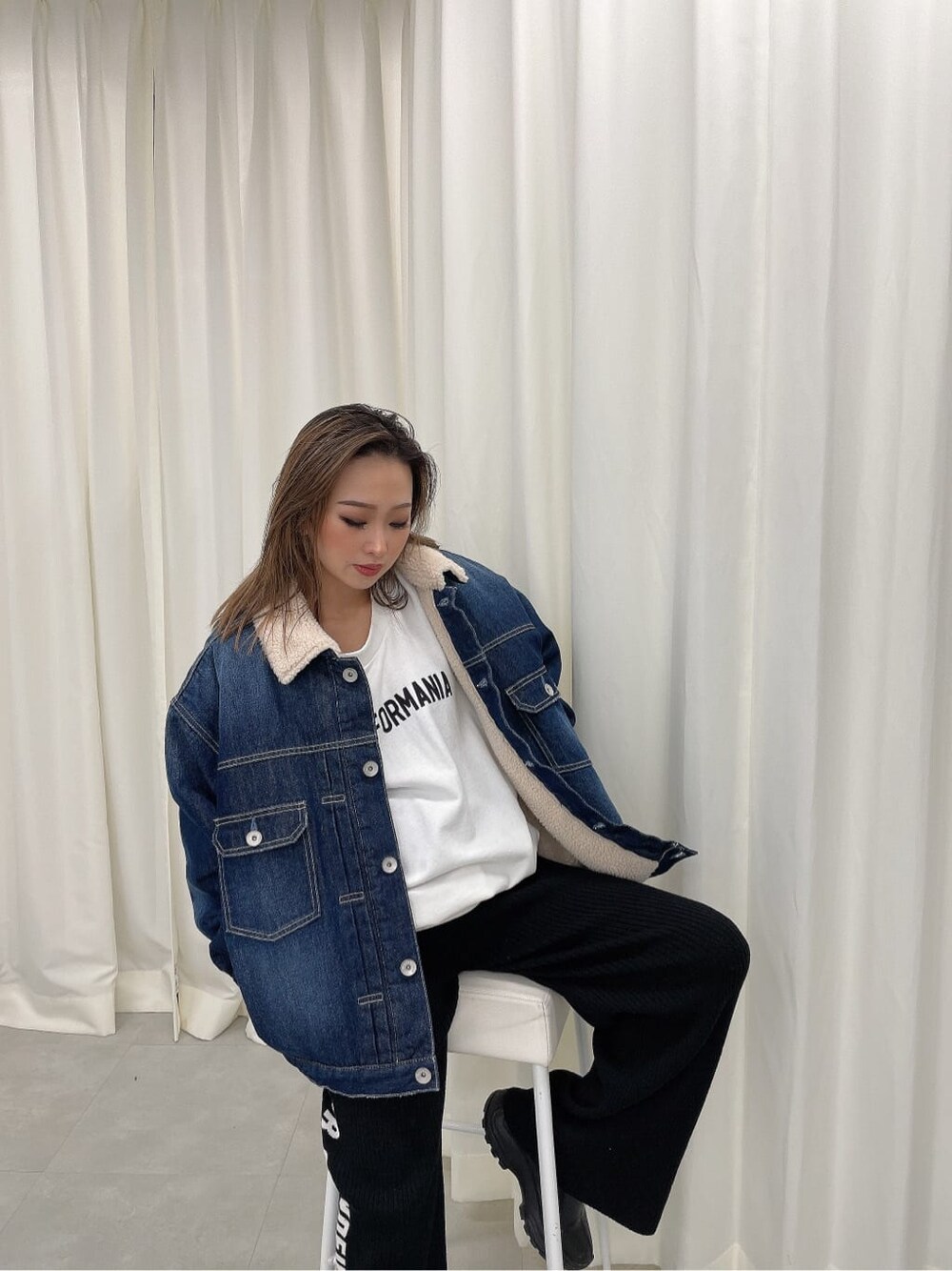 ホワイト系のスウェット、ブルー系のデニムジャケット、ブラック系のその他パンツを着用したレディースの秋コーディネートの3枚目の写真