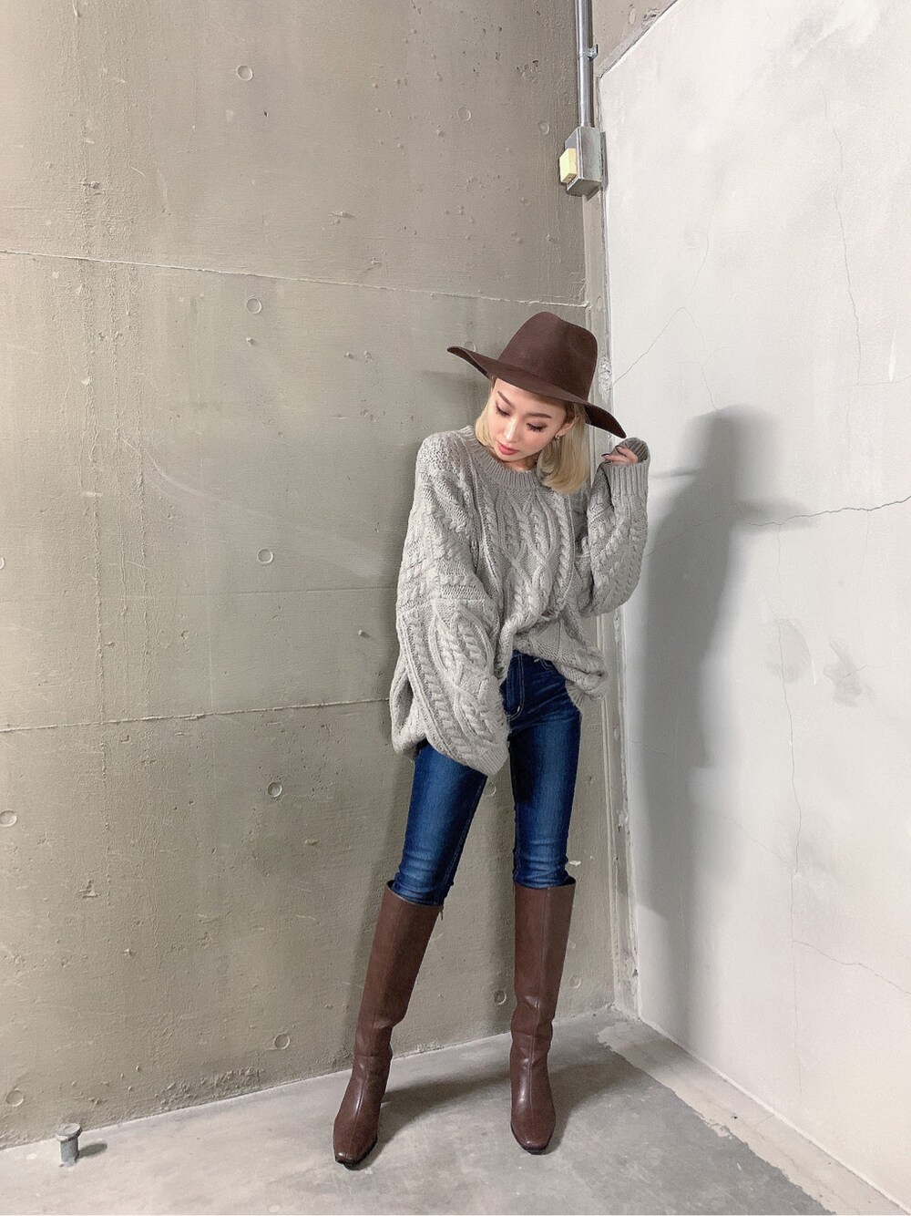ブルー系のデニムパンツ、ブラウン系のブーツ、グレー系のニット/セーターを着用したレディースの秋コーディネートの3枚目の写真