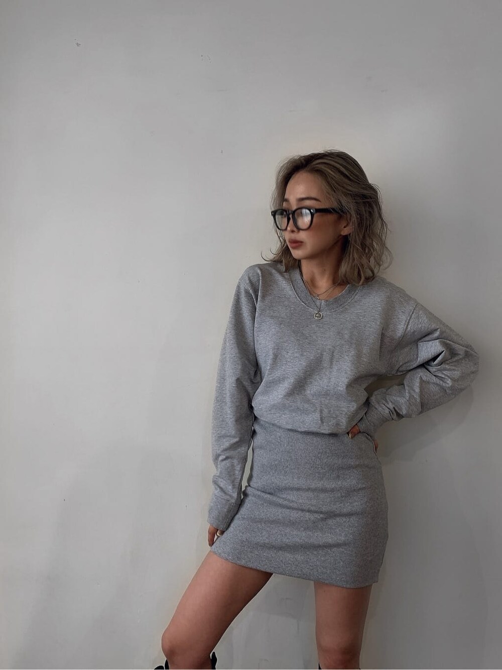 ブラック系のブルゾン、グレー系のワンピース、ブラック系のブーツを着用したレディースの夏コーディネートの4枚目の写真