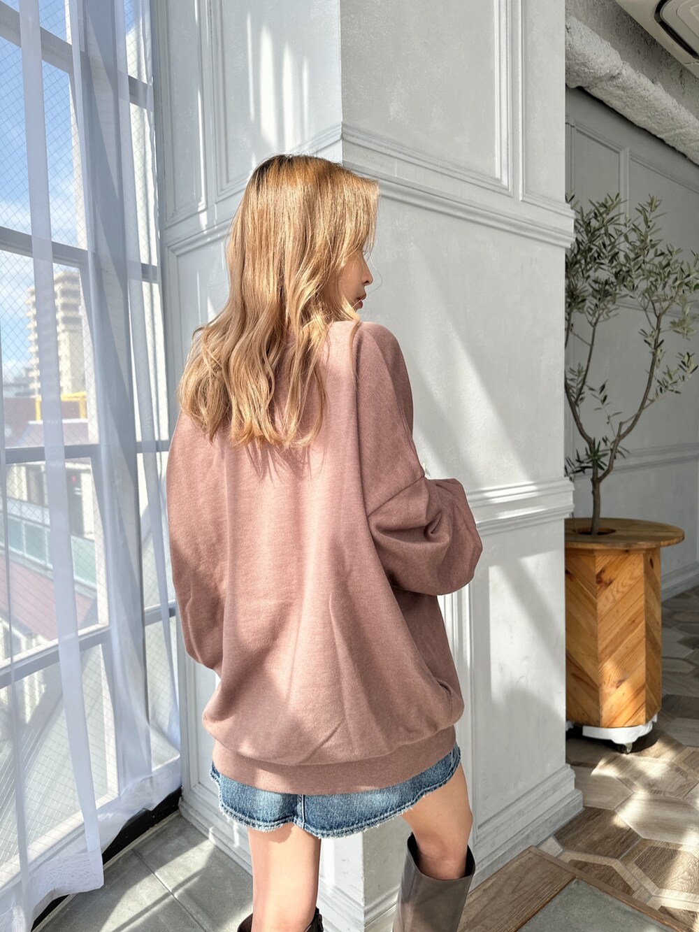 ベージュ系のスウェット、ブルー系のデニムスカート、ブラウン系のブーツを着用したレディースの秋コーディネートの5枚目の写真