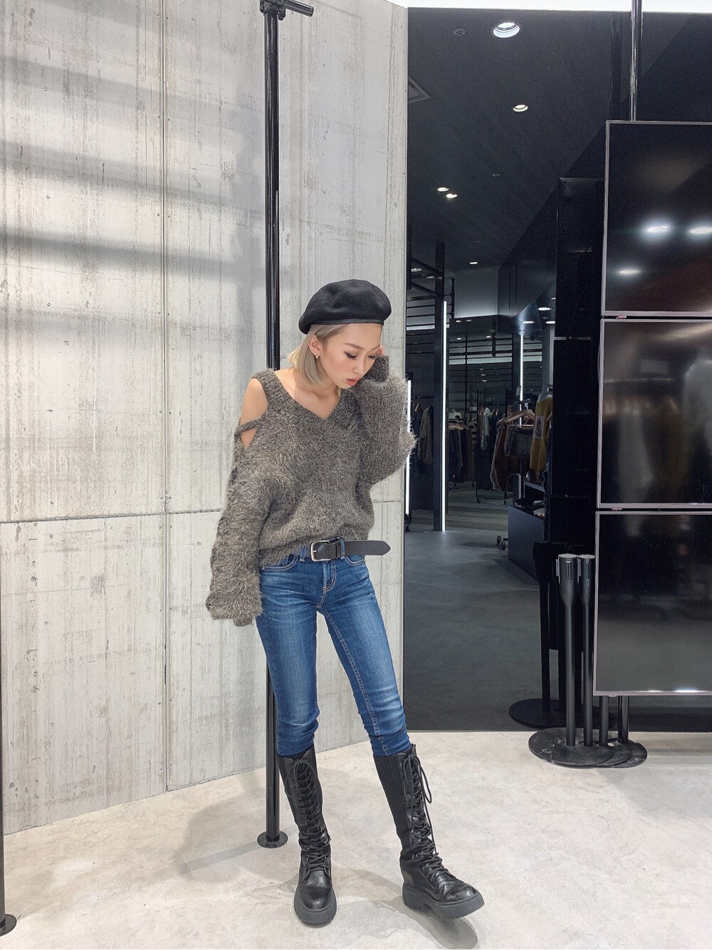 グレー系のニット/セーター、ブルー系のデニムパンツ、ブラック系のブーツを着用したレディースの秋コーディネートの2枚目の写真