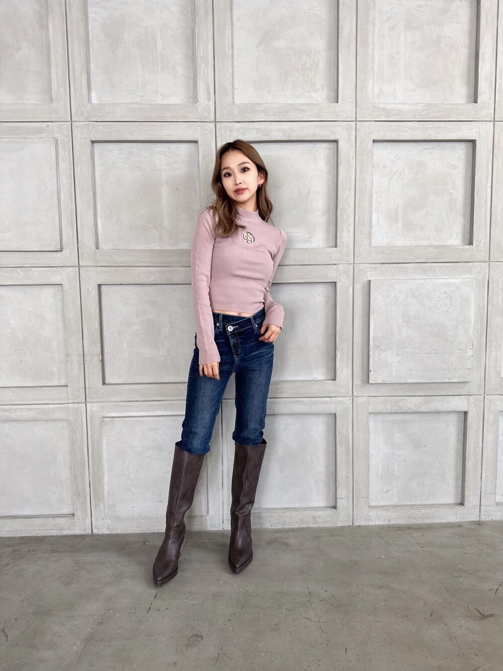 ピンク系のニット/セーター、ブルー系のデニムパンツ、ブラウン系のブーツを着用したレディースの冬コーディネートの2枚目の写真