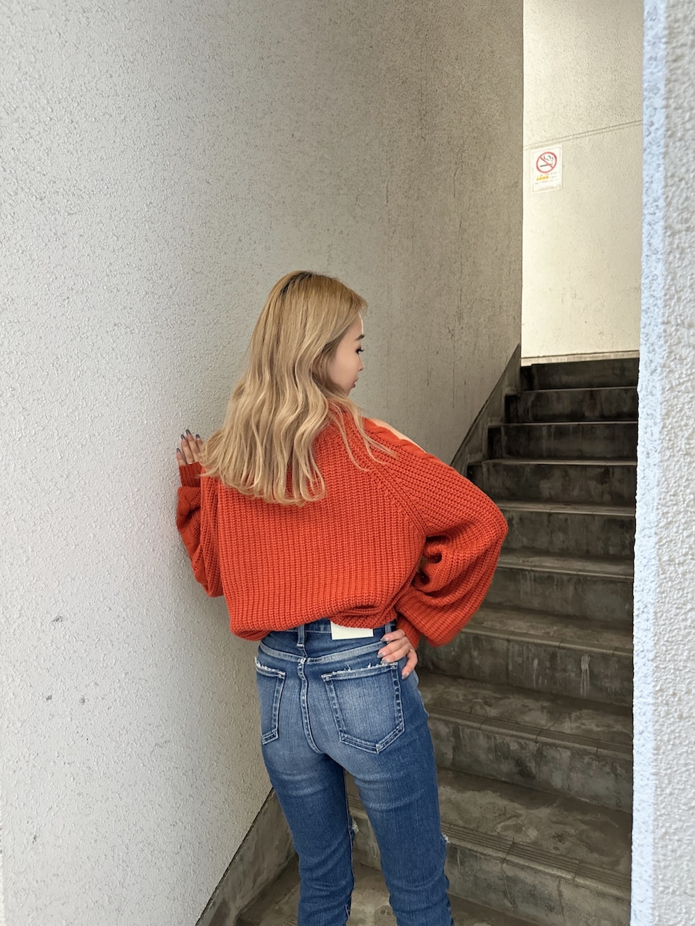 オレンジ系のニット/セーター、ブルー系のデニムパンツ、ブラック系のパンプスを着用したレディースの秋コーディネートの5枚目の写真