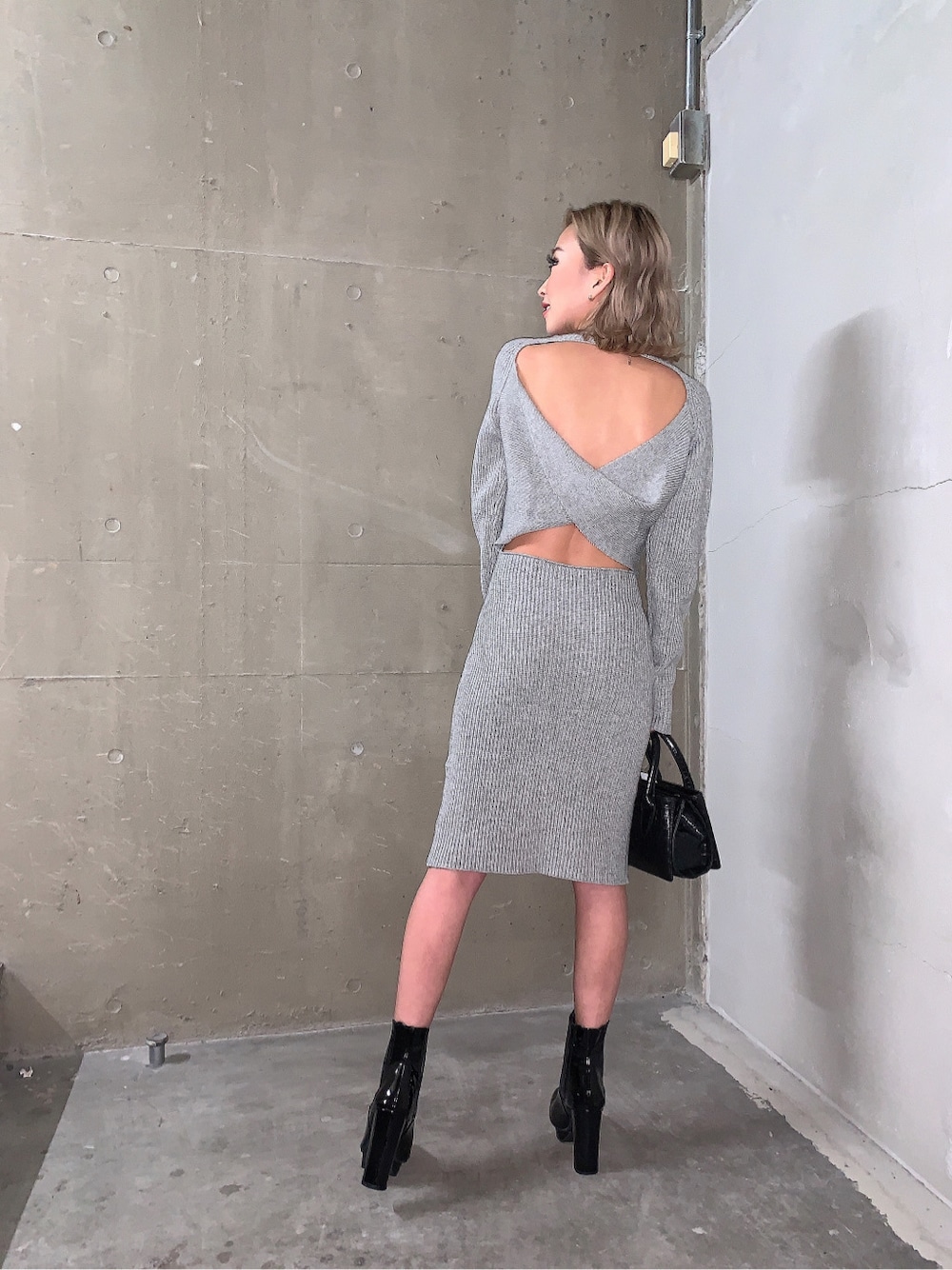 ブラック系のブーツ、グレー系のワンピース、ブラック系のショルダーバッグを着用したレディースの冬コーディネートの2枚目の写真