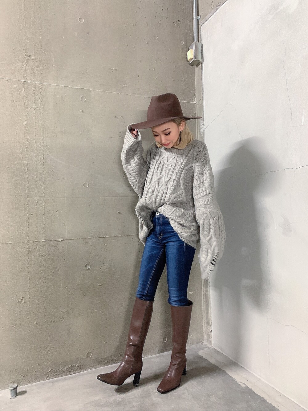 ブルー系のデニムパンツ、ブラウン系のブーツ、グレー系のニット/セーターを着用したレディースの秋コーディネートの2枚目の写真