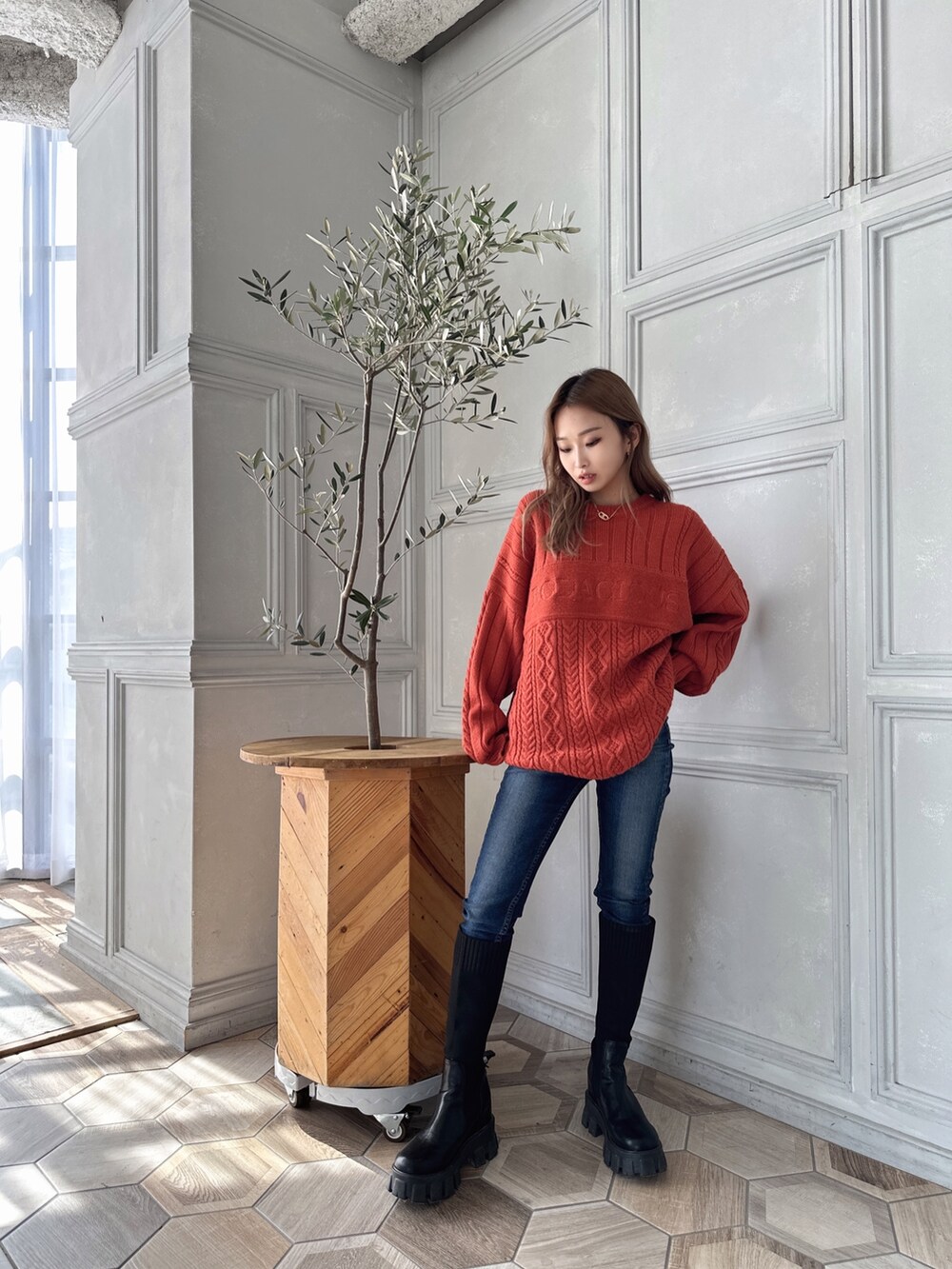 オレンジ系のニット/セーター、ブルー系のデニムパンツ、ブラック系のブーツを着用したレディースの秋コーディネートの3枚目の写真