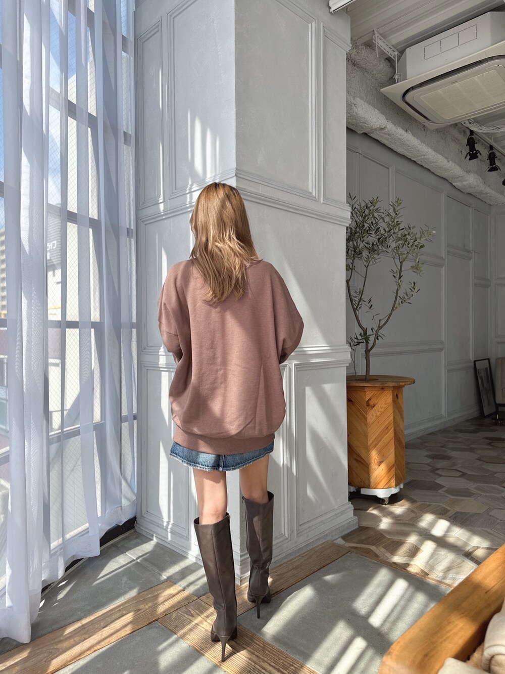 ベージュ系のスウェット、ブルー系のデニムスカート、ブラウン系のブーツを着用したレディースの秋コーディネートの4枚目の写真