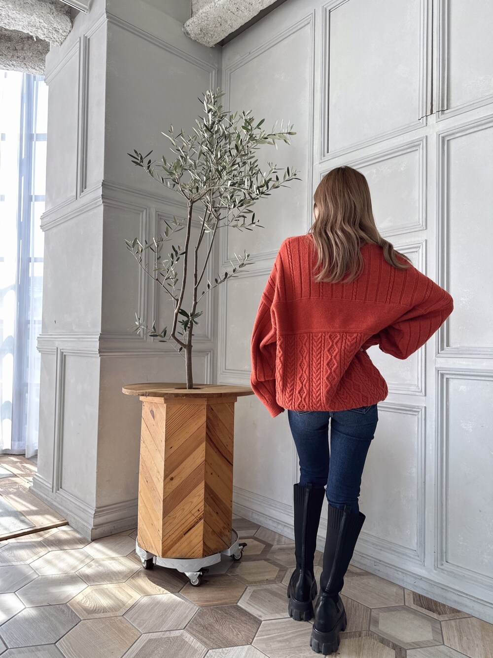 オレンジ系のニット/セーター、ブルー系のデニムパンツ、ブラック系のブーツを着用したレディースの秋コーディネートの5枚目の写真