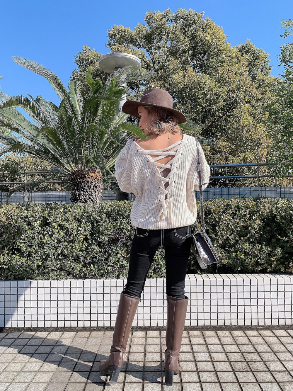 ブラウン系のショルダーバッグ、ベージュ系のキャミソール、ブラック系のデニムパンツを着用したレディースの冬コーディネートの3枚目の写真