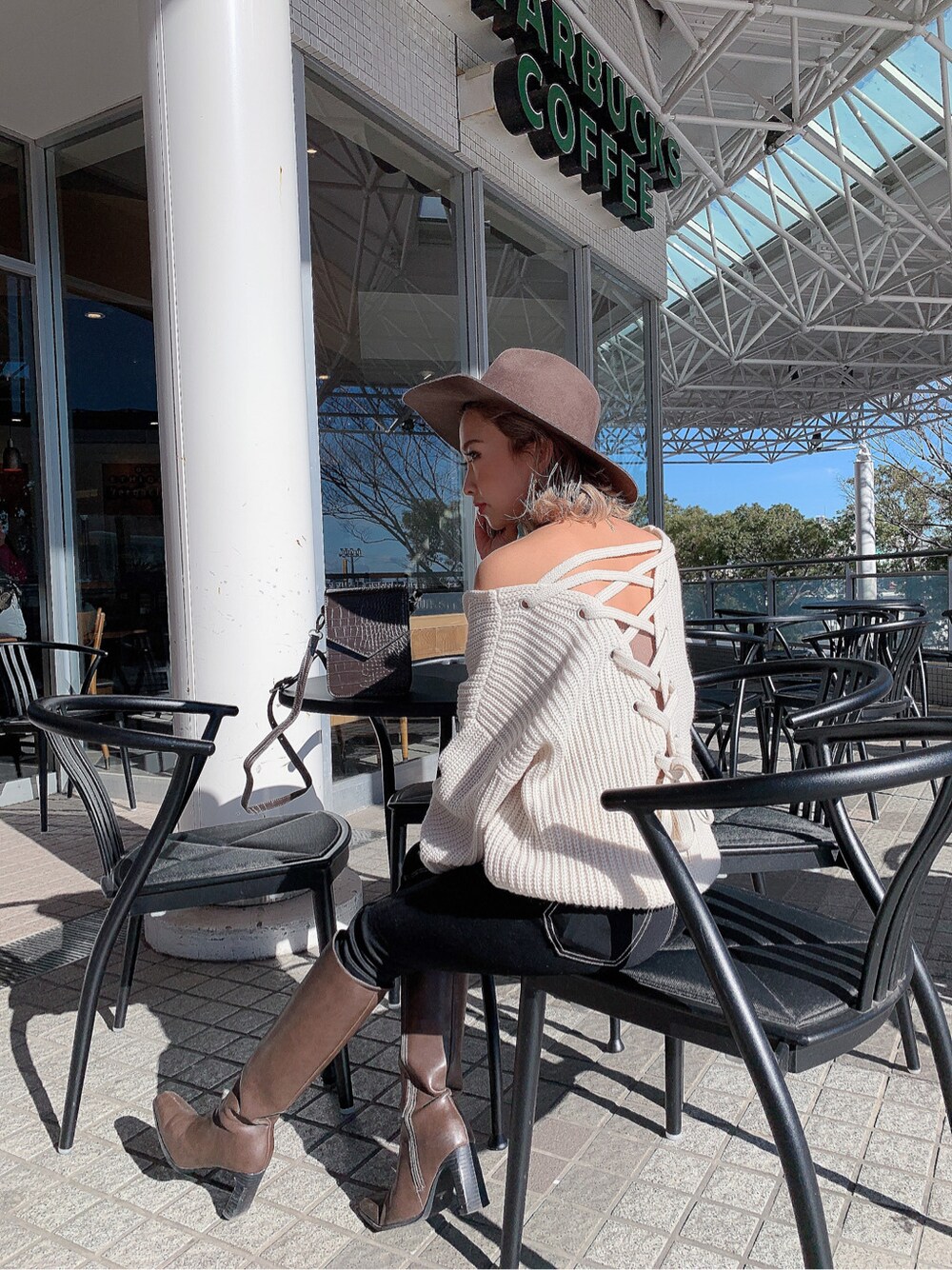 ブラック系のデニムパンツ、ブラウン系のショルダーバッグ、ベージュ系のキャミソールを着用したレディースの冬コーディネートの2枚目の写真