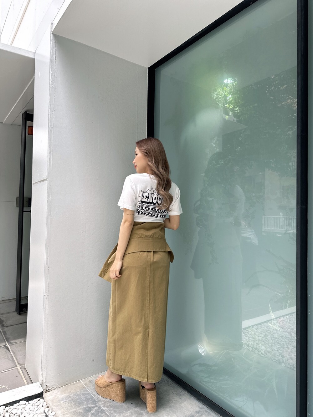 ホワイト系のTシャツ/カットソー、グリーン系のスカート、ベージュ系のサンダルを着用したレディースの春コーディネートの2枚目の写真