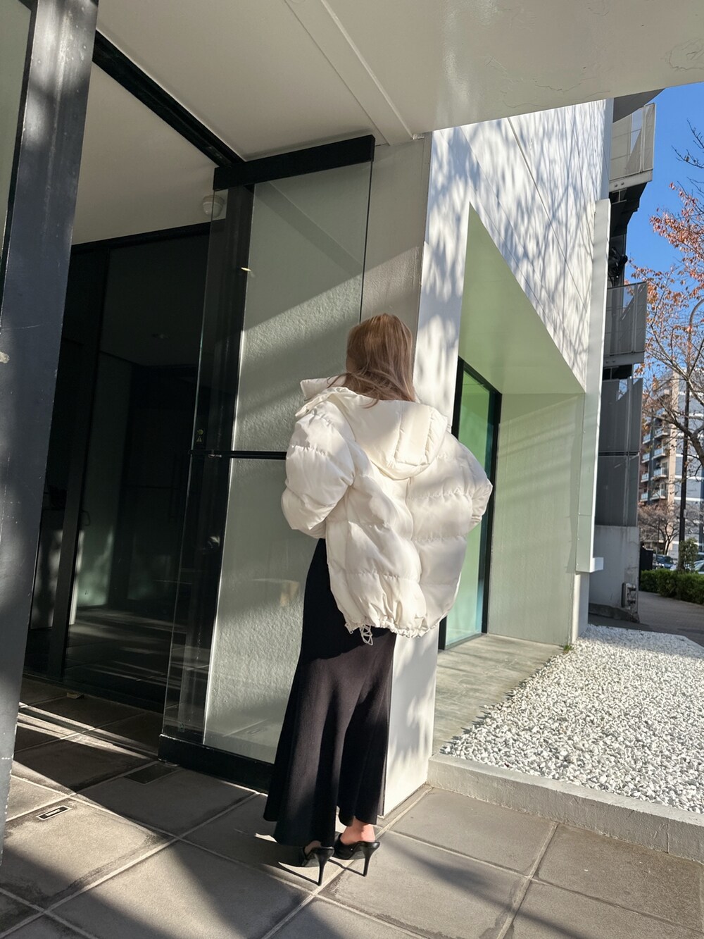 ブラック系のニット/セーター、ブラック系のスカート、ホワイト系のダウンジャケット/コートを着用したレディースの冬コーディネートの2枚目の写真