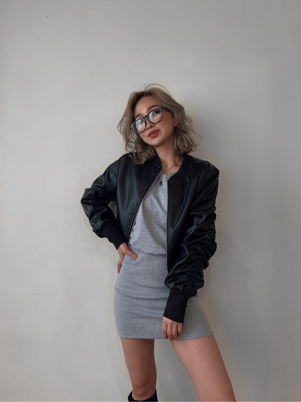 ブラック系のブルゾン、グレー系のワンピース、ブラック系のブーツを着用したレディースの夏コーディネートの2枚目の写真