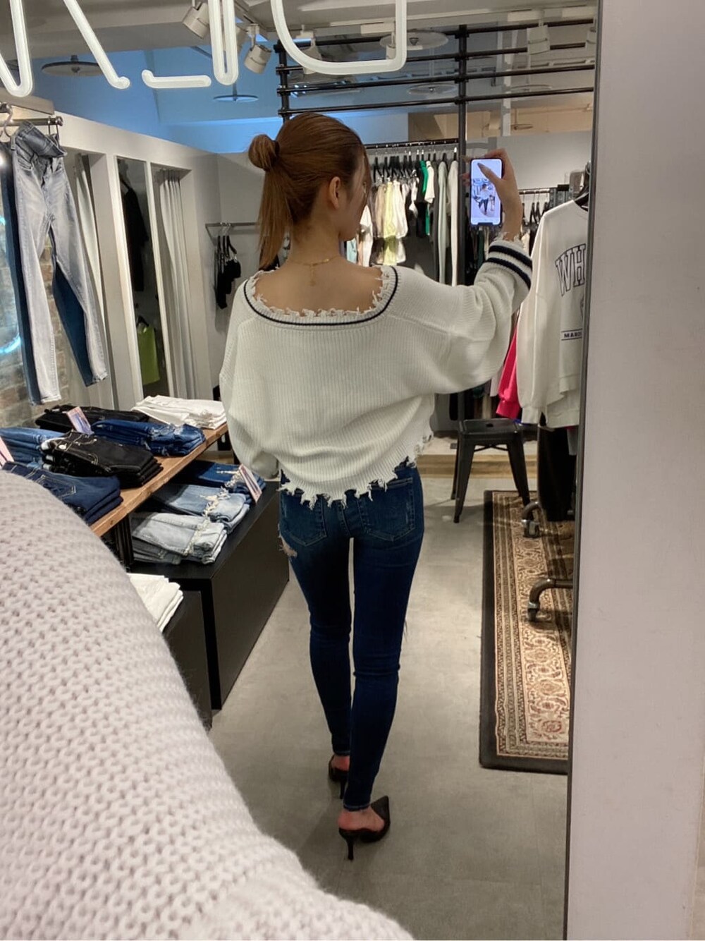 ブラック系のパンプス、ホワイト系のニット/セーター、ブルー系のデニムパンツを着用したレディースの夏コーディネートの4枚目の写真