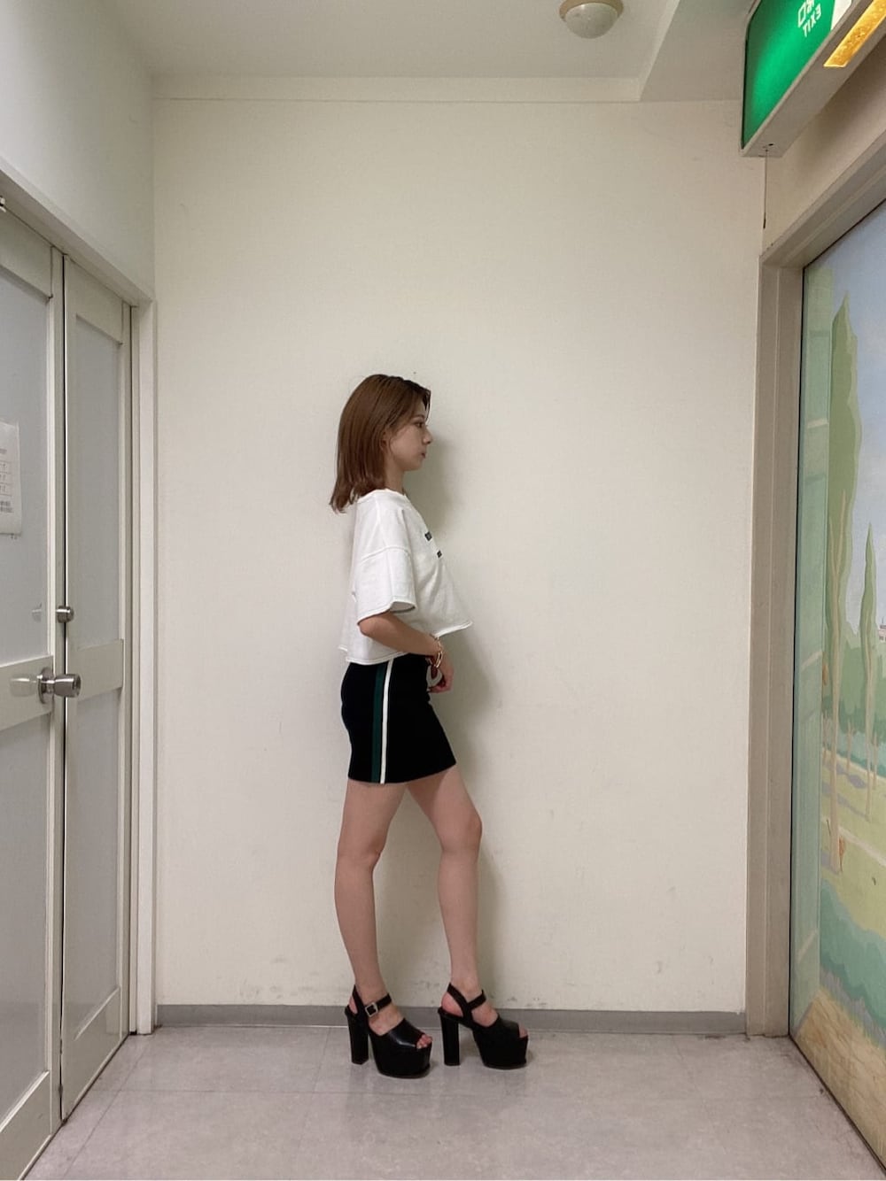 ブラック系のスカート、ブラック系のサンダル、ホワイト系のTシャツ/カットソーを着用したレディースの夏コーディネートの2枚目の写真