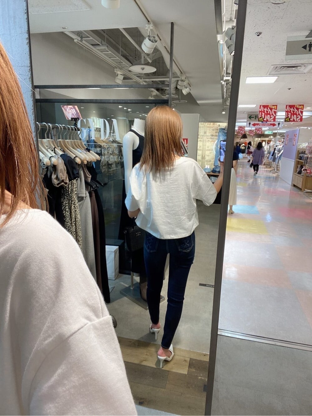 ブルー系のデニムパンツ、ホワイト系のTシャツ/カットソー、ホワイト系のパンプスを着用したレディースの夏コーディネートの2枚目の写真