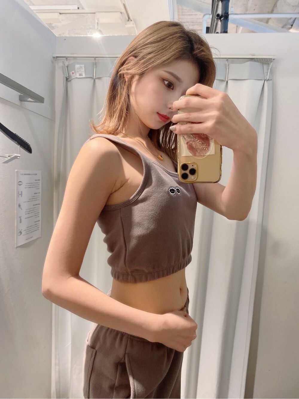 ホワイト系のパンプス、ベージュ系のスウェットパンツ、ベージュ系のタンクトップを着用したレディースの夏コーディネートの3枚目の写真