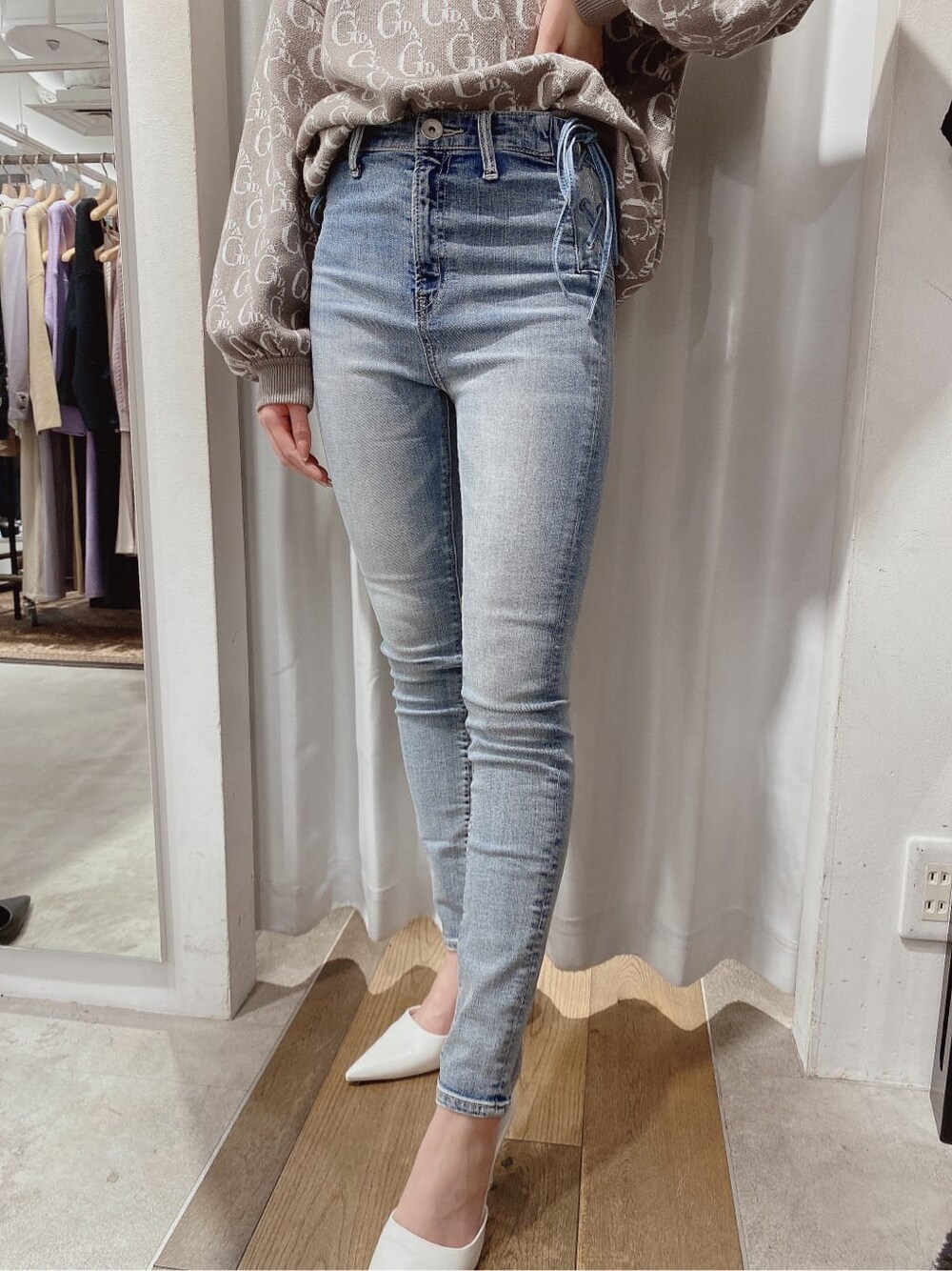 ホワイト系のパンプス、ベージュ系のニット/セーター、ブルー系のデニムパンツを着用したレディースの冬コーディネートの4枚目の写真