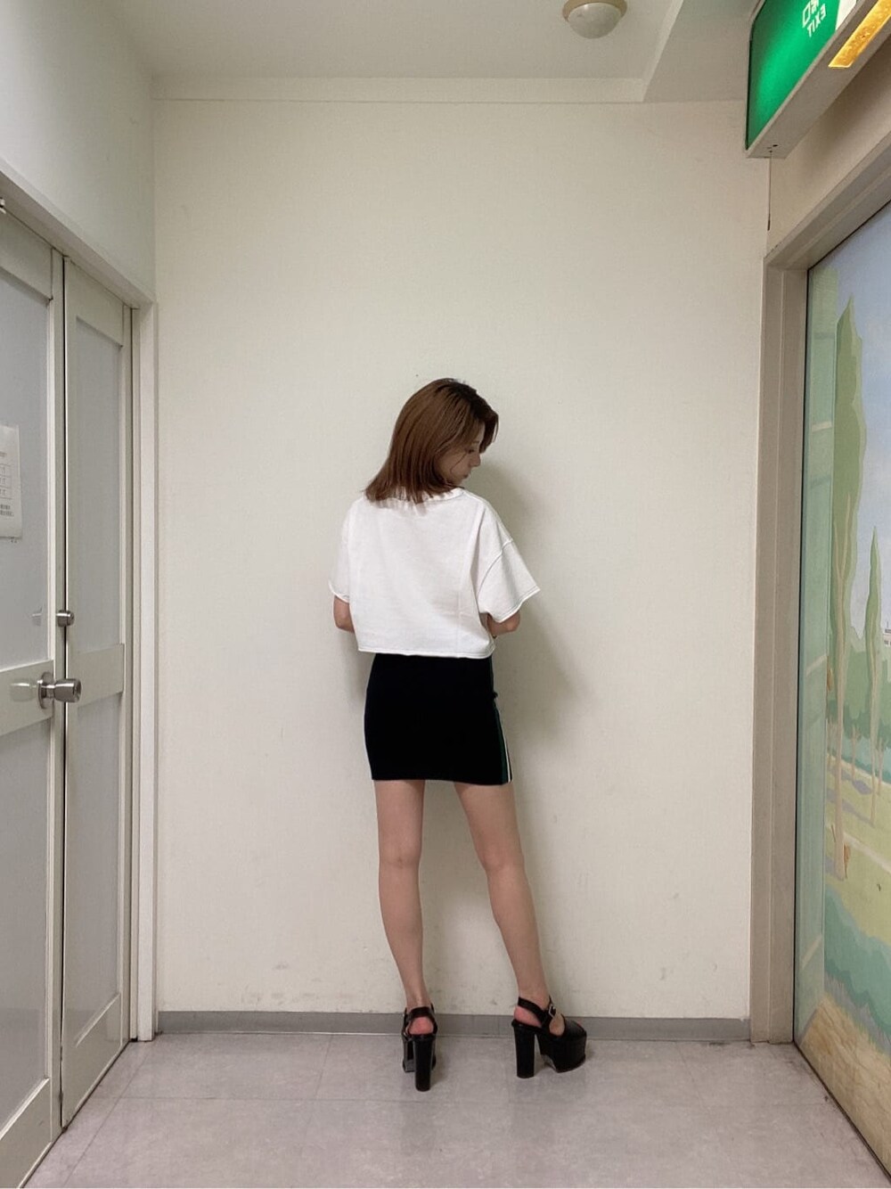 ブラック系のスカート、ブラック系のサンダル、ホワイト系のTシャツ/カットソーを着用したレディースの夏コーディネートの3枚目の写真