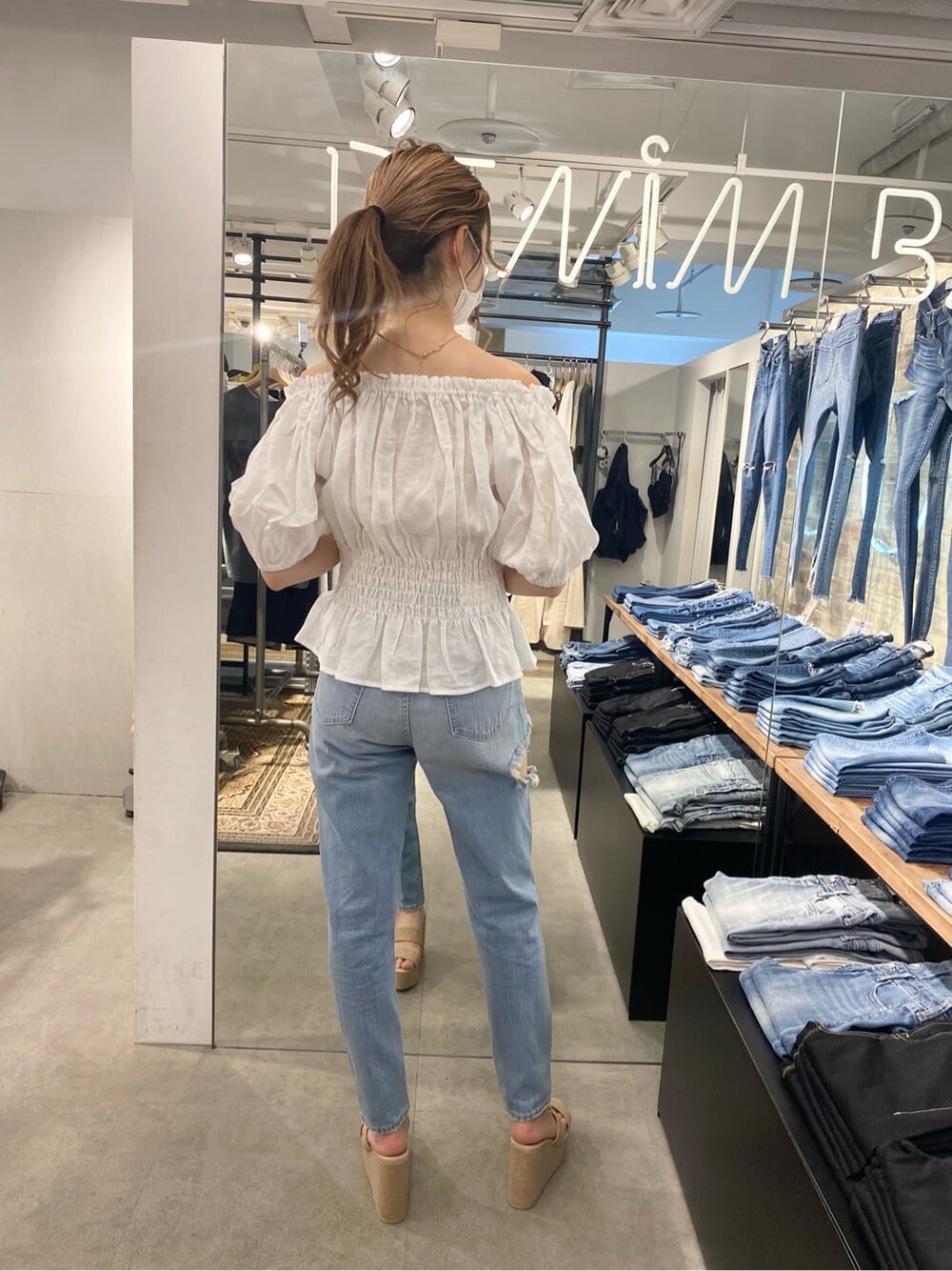 ベージュ系のハンドバッグ、ホワイト系のシャツ/ブラウス、ホワイト系のサンダルを着用したレディースの春コーディネートの2枚目の写真