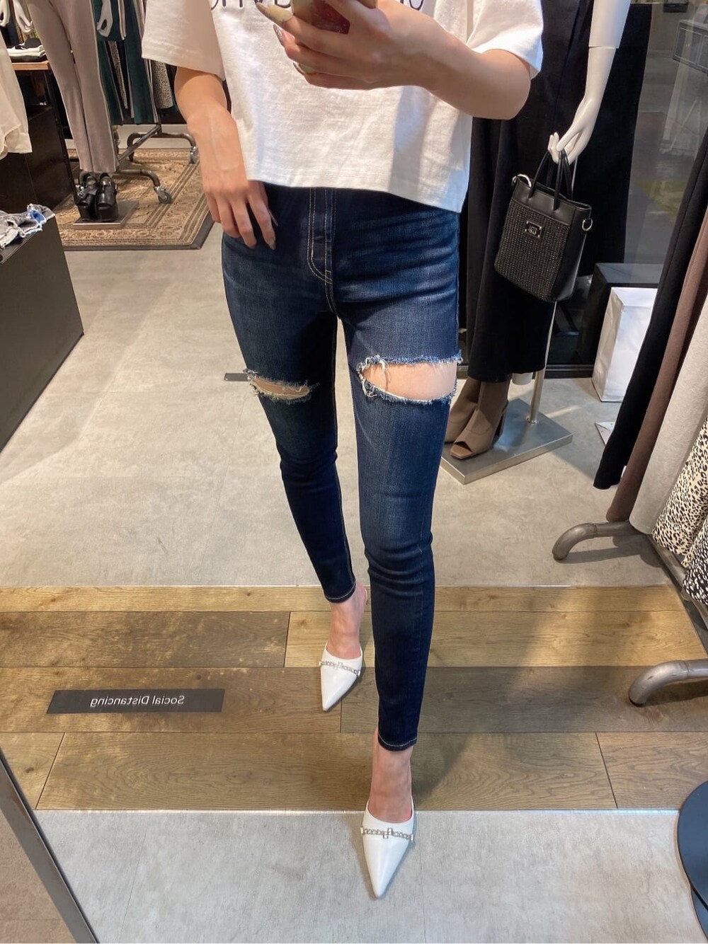 ブルー系のデニムパンツ、ホワイト系のTシャツ/カットソー、ホワイト系のパンプスを着用したレディースの夏コーディネートの4枚目の写真