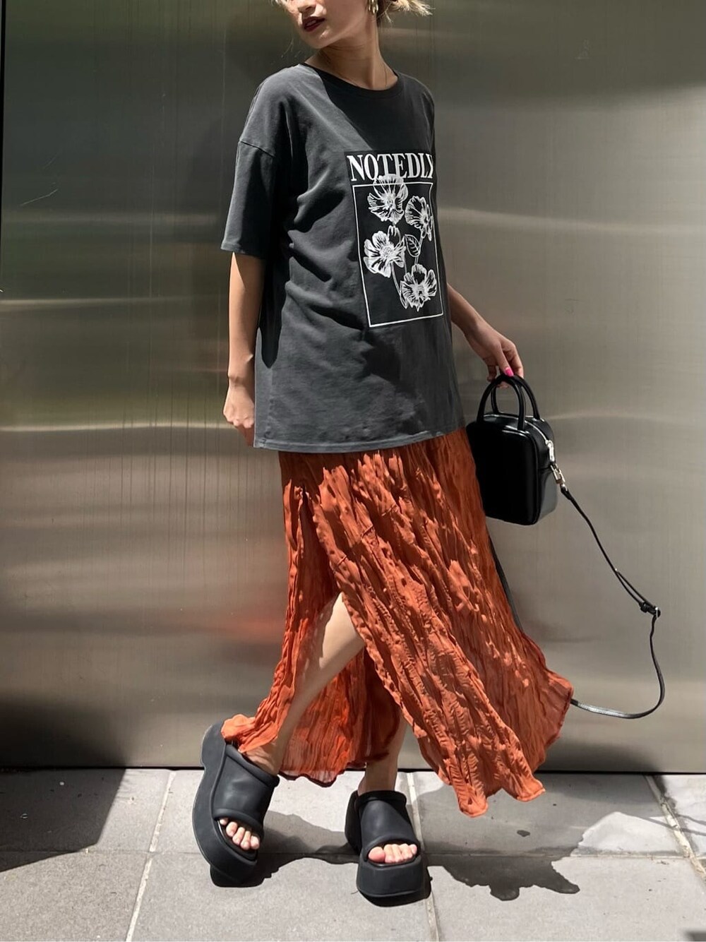 ブラック系のショルダーバッグ、オレンジ系のワンピース、ブラック系のサンダルを着用したレディースの春コーディネートの6枚目の写真