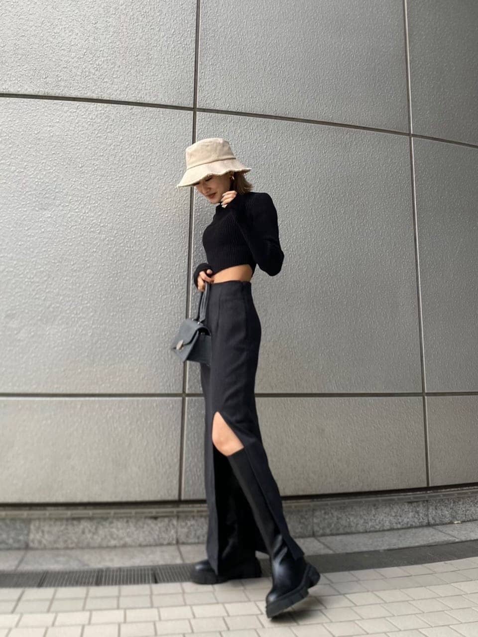 ブラック系のニット/セーター、ブラック系のブーツ、ブラック系のハンドバッグを着用したレディースの冬コーディネートの2枚目の写真