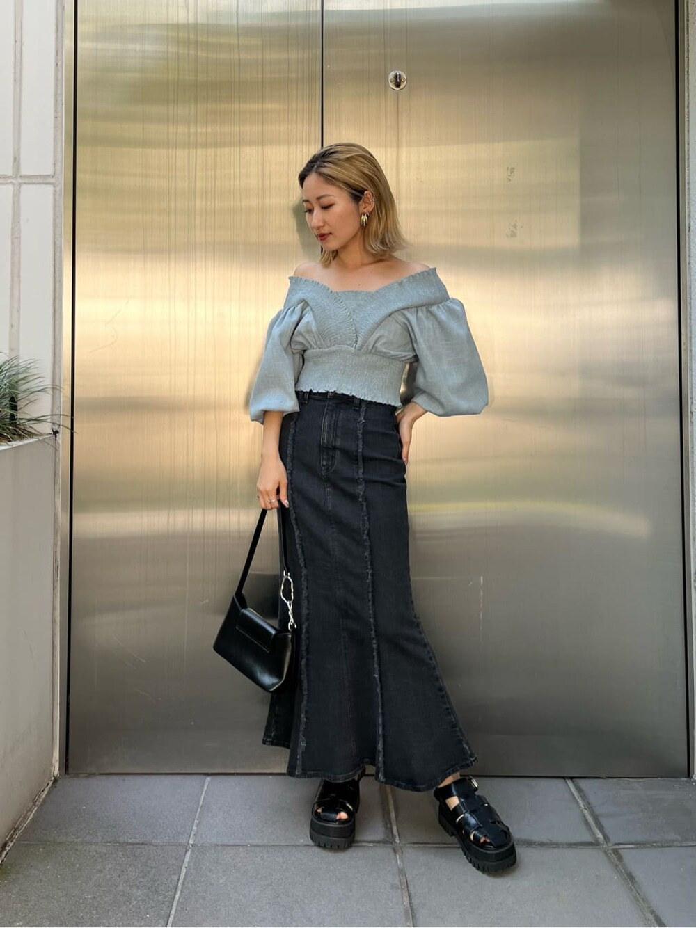 ブラック系のハンドバッグ、ブルー系のスカート、ブルー系のシャツ/ブラウスを着用したレディースの夏コーディネートの3枚目の写真