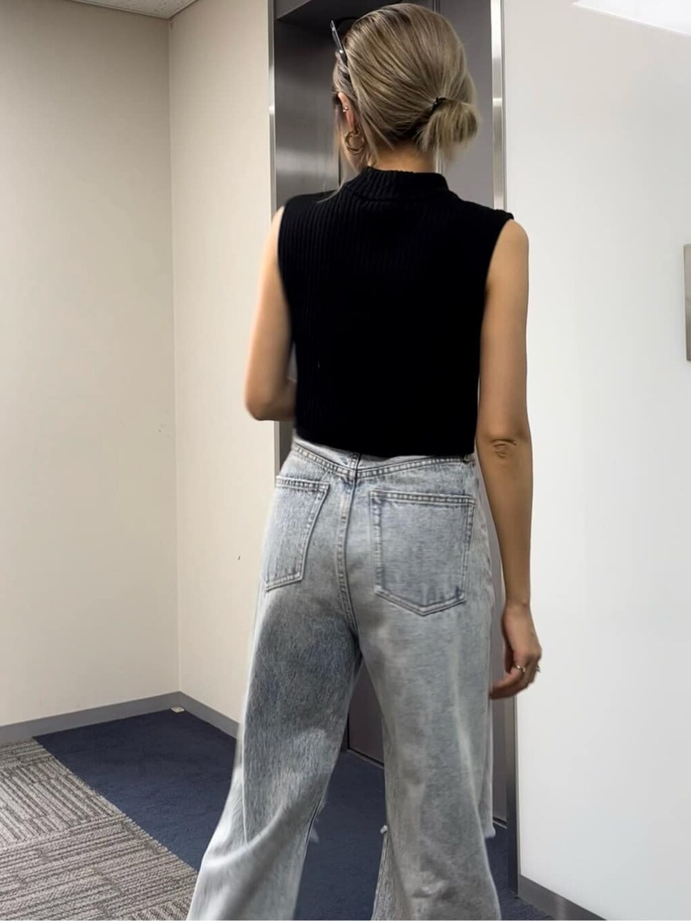 ブラック系のタンクトップ、ブラック系のサンダル、ブルー系のデニムパンツを着用したレディースの夏コーディネートの5枚目の写真