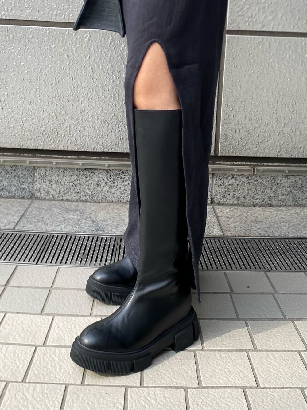 ブラック系のニット/セーター、ブラック系のブーツ、ブラック系のハンドバッグを着用したレディースの冬コーディネートの9枚目の写真