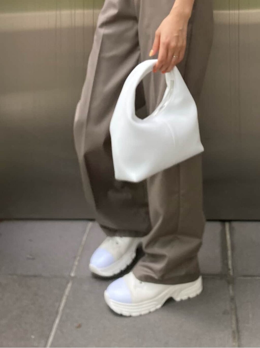 ホワイト系のスニーカー、ブラック系のハンドバッグを着用したレディースの春コーディネートの6枚目の写真