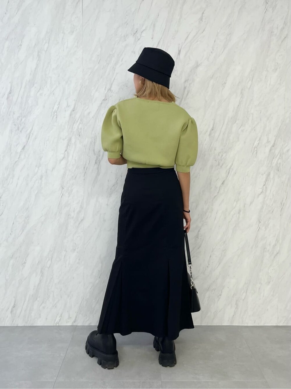 ブラック系のブーツ、ブラック系のスカート、イエロー系のニット/セーターを着用したレディースの春コーディネートの4枚目の写真