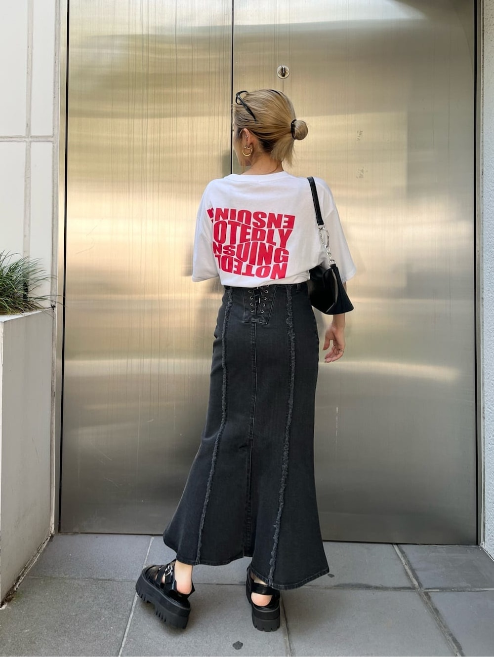 ブラック系のハンドバッグ、ブラック系のスカート、ホワイト系のTシャツ/カットソーを着用したレディースの夏コーディネートの3枚目の写真