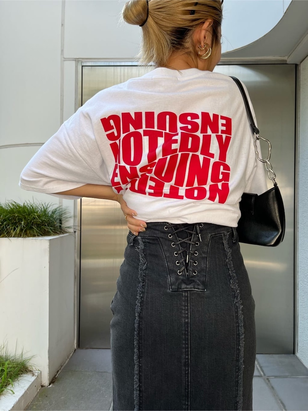 ブラック系のハンドバッグ、ブラック系のスカート、ホワイト系のTシャツ/カットソーを着用したレディースの夏コーディネートの4枚目の写真