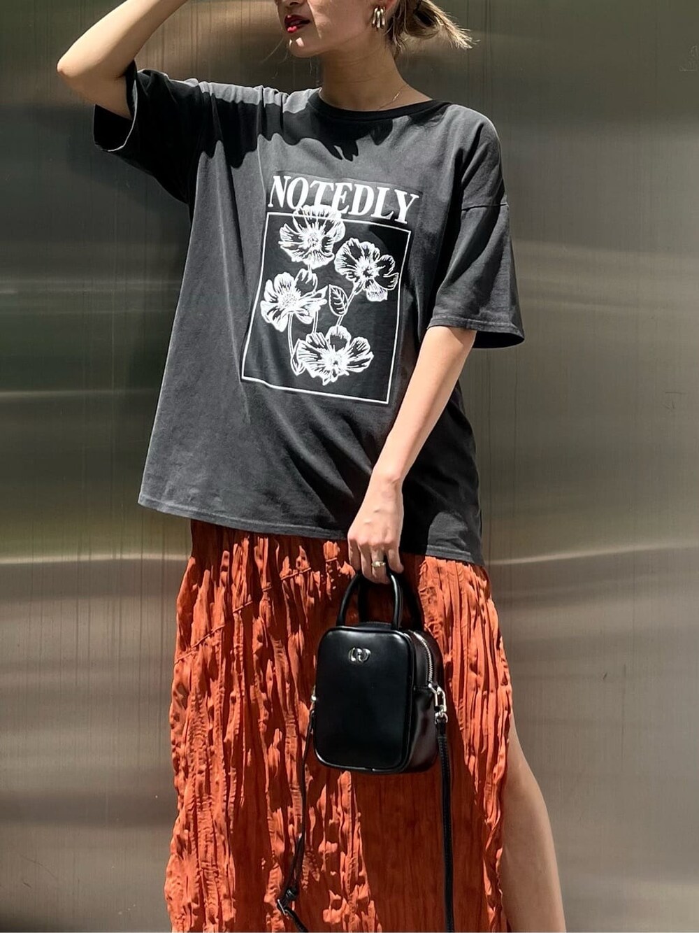 ブラック系のショルダーバッグ、オレンジ系のワンピース、ブラック系のサンダルを着用したレディースの春コーディネートの5枚目の写真