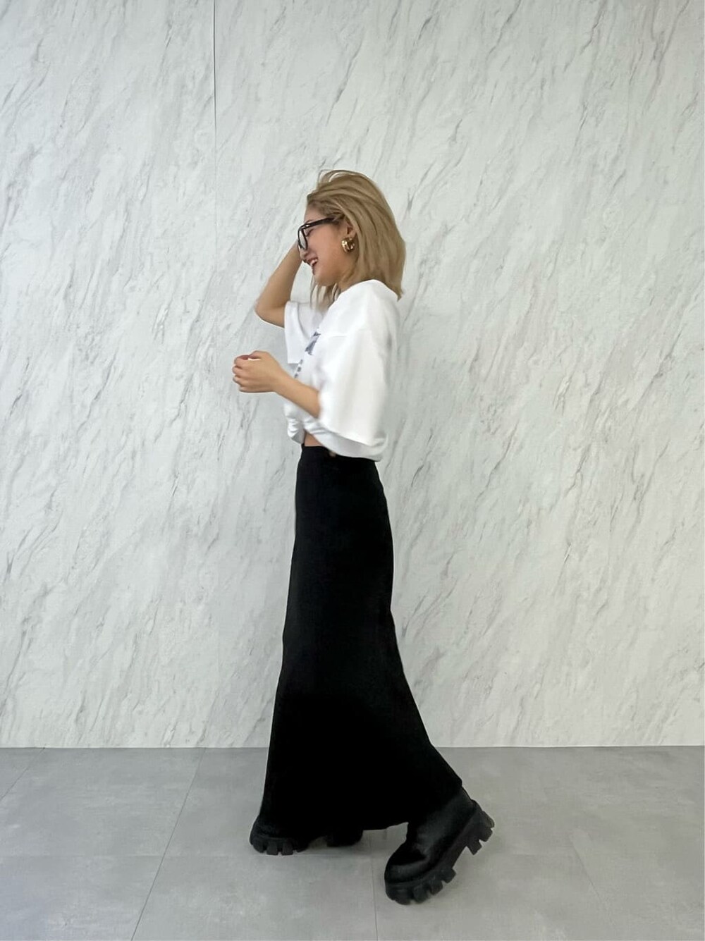 ブラック系のブーツ、ブラック系のスカート、ホワイト系のTシャツ/カットソーを着用したレディースの春コーディネートの3枚目の写真