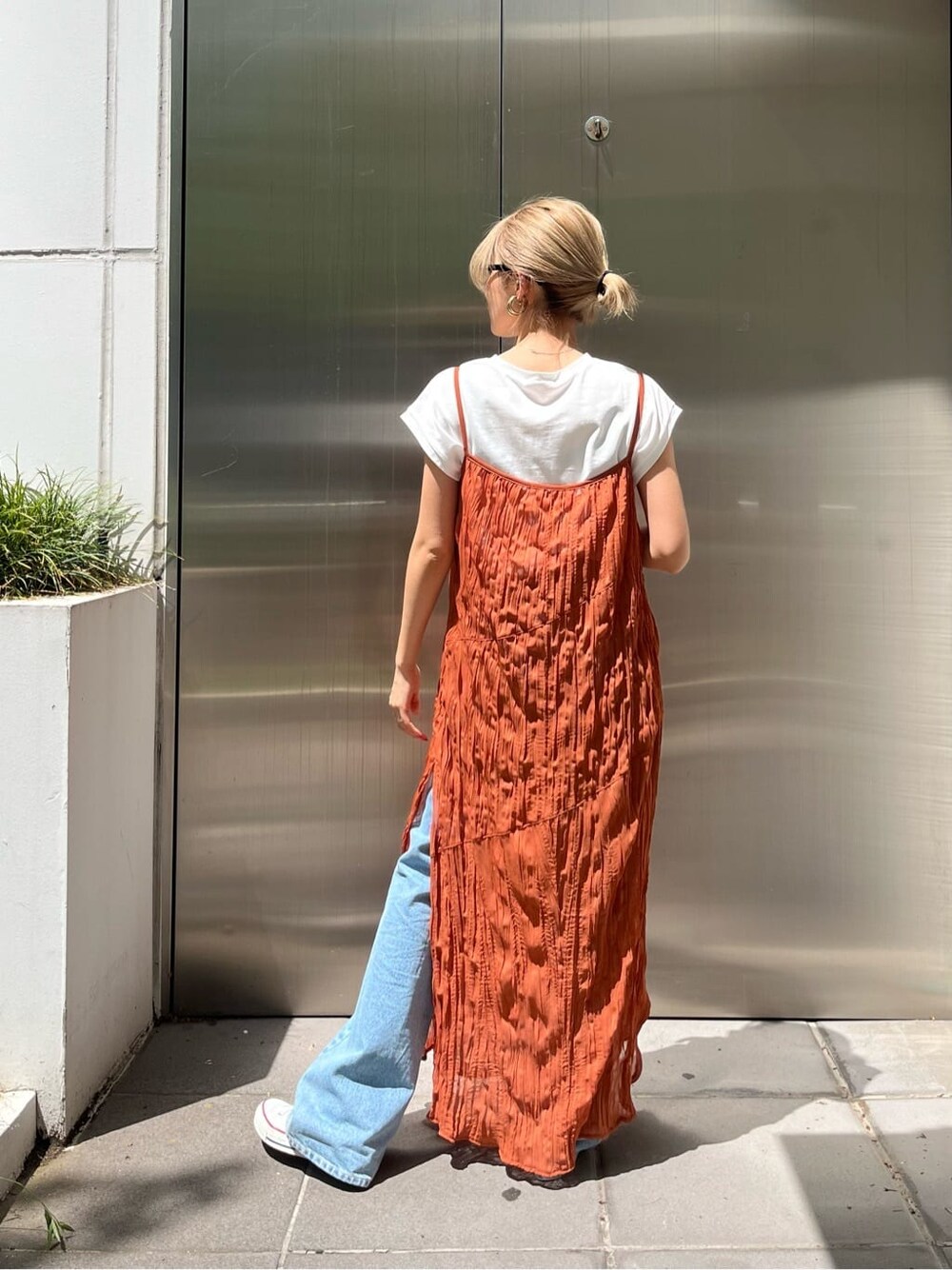 オレンジ系のワンピース、ブルー系のデニムパンツを着用したレディースの春コーディネートの5枚目の写真