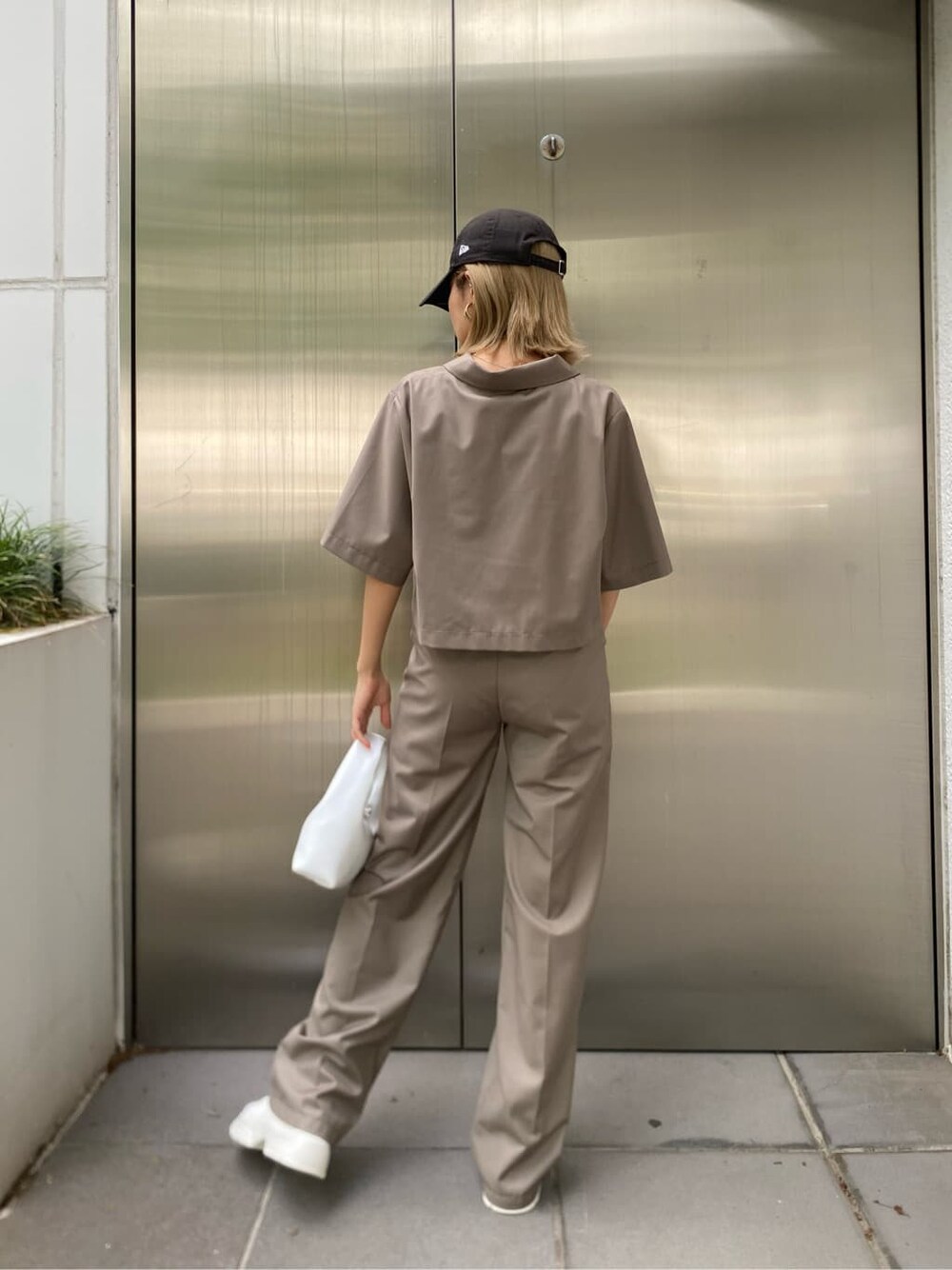 ホワイト系のスニーカー、ブラック系のハンドバッグを着用したレディースの春コーディネートの4枚目の写真