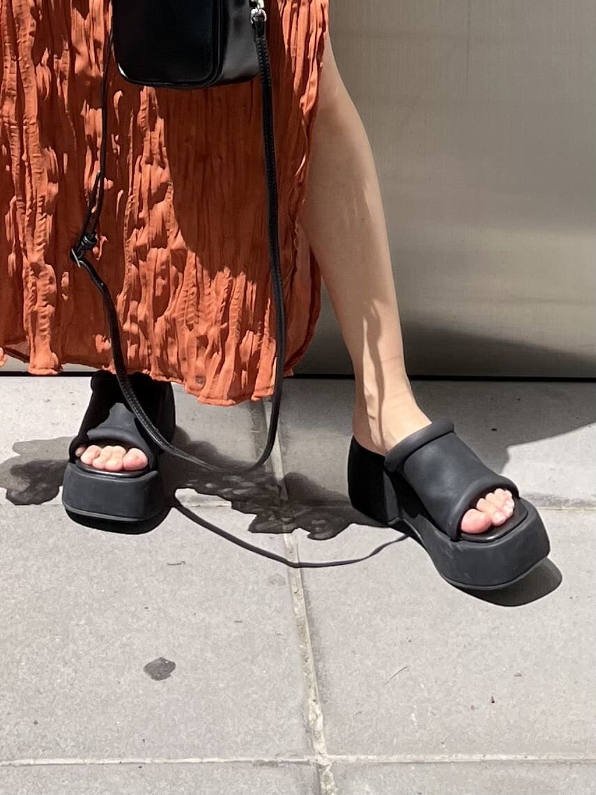 ブラック系のショルダーバッグ、オレンジ系のワンピース、ブラック系のサンダルを着用したレディースの春コーディネートの8枚目の写真