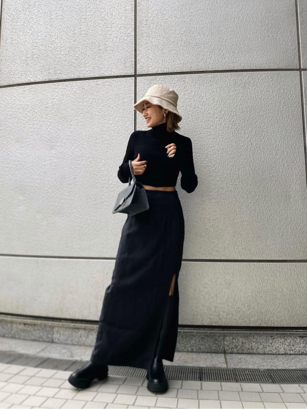 ブラック系のニット/セーター、ブラック系のブーツ、ブラック系のハンドバッグを着用したレディースの冬コーディネートの3枚目の写真