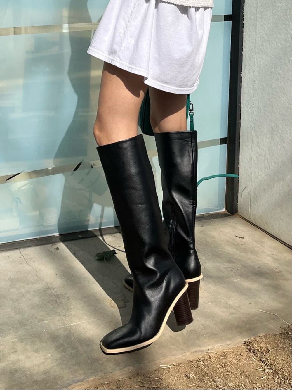 ブラック系のブーツ、ホワイト系のTシャツ/カットソー、ベージュ系のトレンチコートを着用したレディースの春コーディネートの10枚目の写真