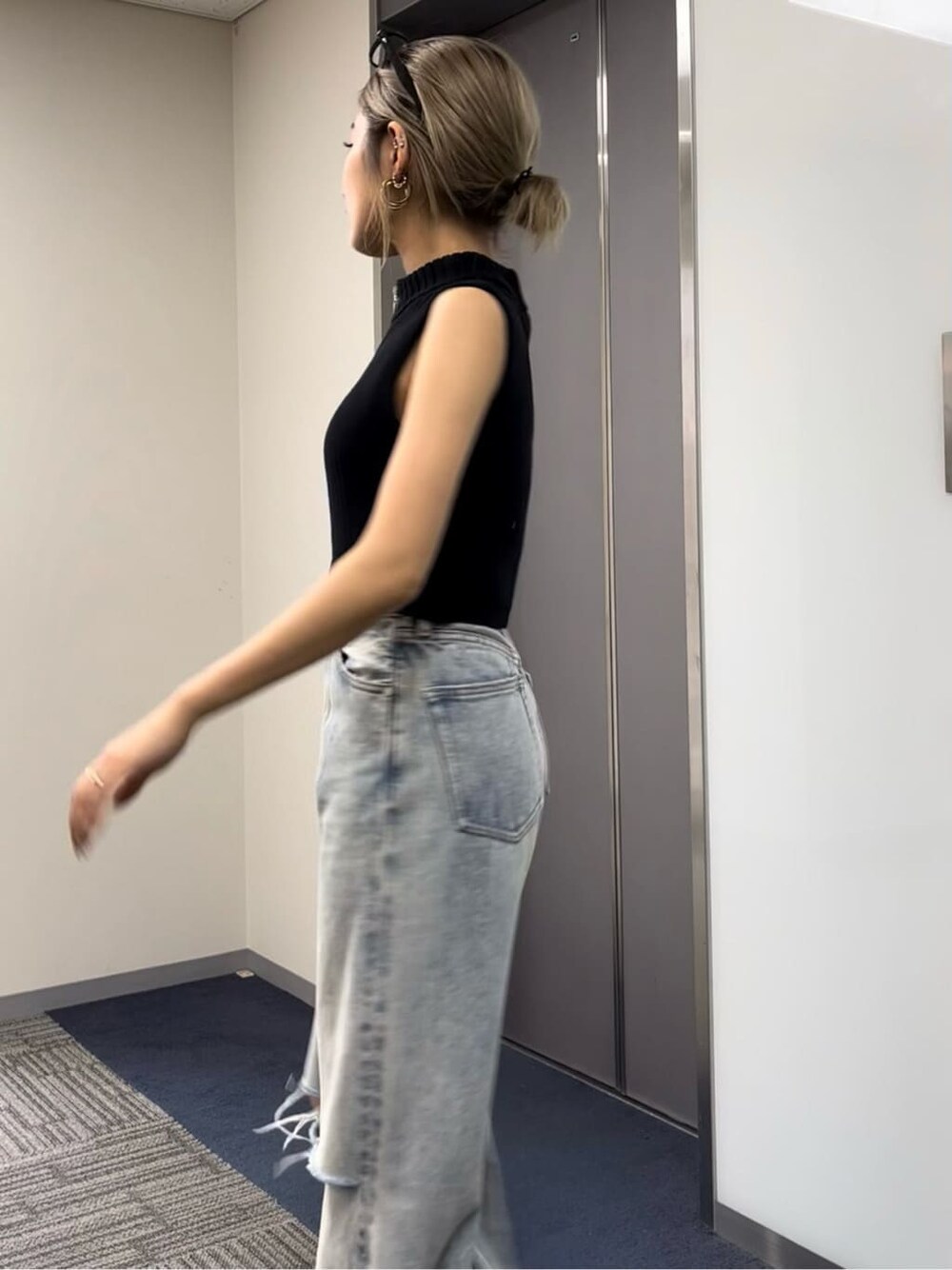 ブラック系のタンクトップ、ブラック系のサンダル、ブルー系のデニムパンツを着用したレディースの夏コーディネートの4枚目の写真